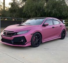 a pink car parked in front of a fence