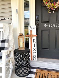 a black and white front door with a welcome sign on the porch next to it