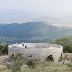 two people sitting on top of a large circular structure in the middle of a field