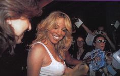 a woman is signing autographs for fans at a party with other people in the background