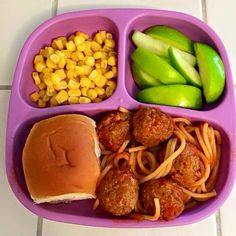 a purple plate topped with spaghetti and meatballs next to corn on the cob