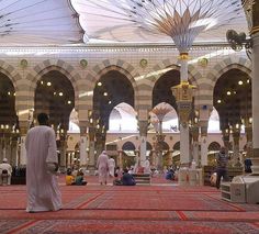 the inside of a large building with people sitting and standing around it, all in white