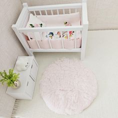 a white crib with pink bedding and pillows