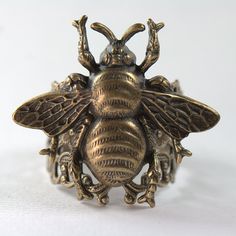 Bee my Honey Bee Ring in Antiqued Bronze-Gold Or in Silver. Bees really are creatures of contradiction because the aerodynamics of their body shape should dictate that flight isn't possible. Yet, they zip through the air in happy, meandering paths with amazing speed and grace, searching for blossoms. Oh, we could learn a valuable lesson from them and not limit our possibilities or ourselves by what others say we cannot do. Would make the perfect gift for you or for that someone special. This gen Steampunk Rings, Bee Ring, Bee Inspired, Brown Wedding, How To Clean Metal, Gold Cocktail, Honey Brown, Bronze Gold, White Gift Boxes