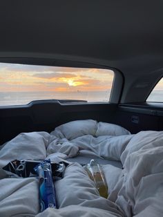 an unmade bed in the back of a car with white sheets and pillows on it