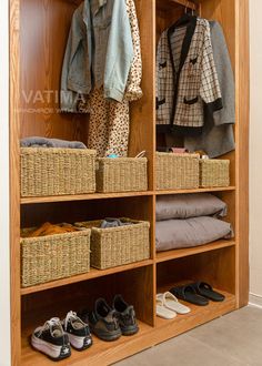 a wooden closet with baskets and clothes hanging on the wall next to it's doors