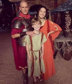 a man and two children dressed up in roman costumes, standing next to each other