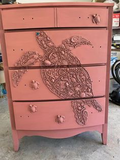 a pink dresser with an intricate turtle design on the front and sides, painted in light pink