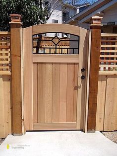 a wooden gate with an iron grill on the top and bottom, in front of a house