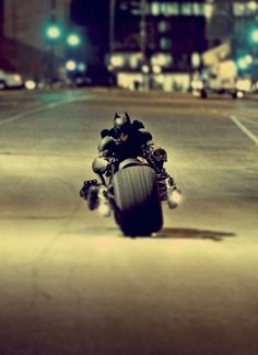 a person riding a motorcycle on a city street at night with the headlights turned on