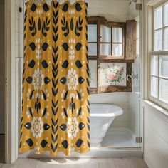 a yellow shower curtain with black and white flowers on it in a bathroom next to a bathtub