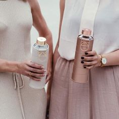 two women standing next to each other holding bottles