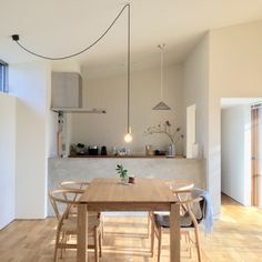 a dining room table and chairs in front of an open kitchen area with wooden flooring