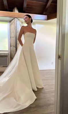 a woman in a white wedding dress is posing for the camera