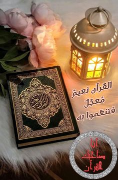 an illuminated lantern next to a book on a fur covered surface with peonies in the background