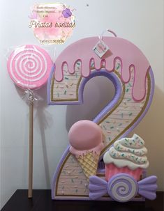 the number two is made out of fondant and decorated with ice cream, lollipops, and sprinkles