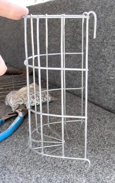 a person is using scissors to cut the wire on top of a metal rack that has been placed in front of a gray couch