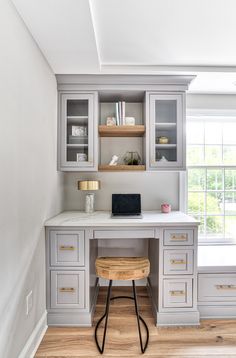 a home office with built - in desk, shelves and drawers on either side of the window