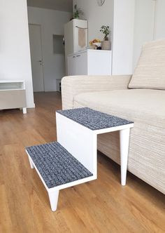 a white couch sitting next to a small table on top of a hard wood floor