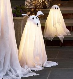 three lighted ghost decorations sitting on the ground