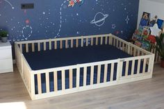 a child's bed with space theme painted on the wall and wooden slats