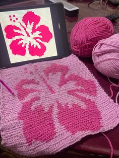 a laptop computer sitting on top of a table next to balls of yarn and crochet