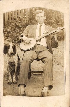 an old black and white photo of a man sitting on a bench with a dog