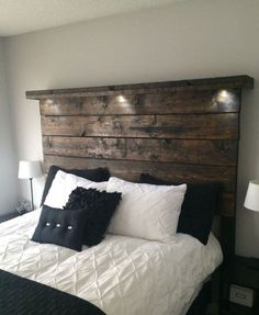 a bed with black and white pillows on it's headboard in a bedroom