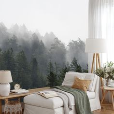 a living room with a couch, table and chair in front of a forest wall mural