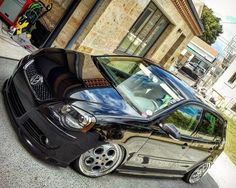 a small black car parked in front of a building