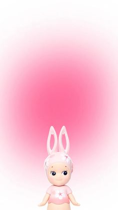 a little doll with bunny ears on it's head sitting in front of a pink background