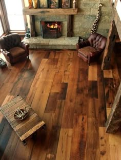 a living room filled with furniture and a fire place next to a wooden floored wall