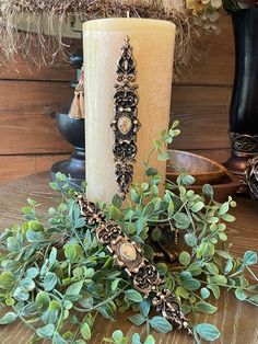 a candle sitting on top of a wooden table next to some green leaves and plants