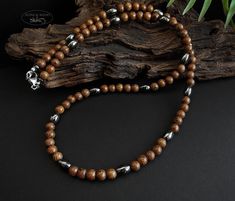 Necklace with 6 mm beautifully patterned Mundambi wood beads and dark silver hematite bean beads. Mounted on sturdy coated stainless steel wire with a stainless steel carabiner clasp Mens Pearl Necklace, Pearl Necklace Men, Surfer Necklace, Necklace Men, Wooden Necklace, Stainless Steel Wire, Necklace Gift, Wood Beads, Men Necklace