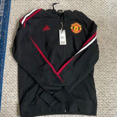 Adidas Branded Manchester United Hoodie With Red And White Stripes Down The Sleeves. New With Tags! Adidas Track Jacket With Drawstring Hood, Adidas Hooded Long Sleeve Jacket For Streetwear, Adidas Long Sleeve Track Jacket With Drawstring Hood, Adidas Sports Hoodie Outerwear, Adidas Red Winter Sweatshirt, Adidas Red Sweatshirt For Winter, Adidas Long Sleeve Hooded Sportswear Jacket, Adidas Sportswear Long Sleeve Hooded Jacket, Adidas Sportswear Hooded Jacket