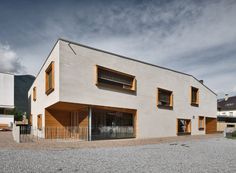 a large white building with wooden shutters on the front and side windows, in an open area