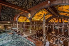 the inside of a restaurant with many tables and stools in front of an ornate iron fence