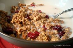 a bowl filled with cereal and cranberries on top of a red table cloth