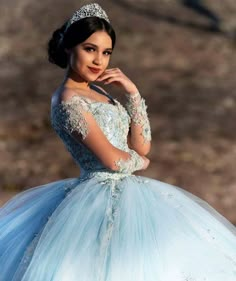 a woman wearing a blue dress and tiara posing for a photo with her hand on her chin