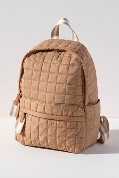 Carry your essentials in style with Shiraleah's Ezra Backpack. This trendy yet practical knapsack is made from nylon and with a chic and casual quilted design. Measuring L 12" × W 7" × H1 5" and equipped with adjustable straps, the Ezra Backpack is the perfect addition to your favorite everyday casual outfit. You can wear it over one shoulder or both for a hands-free look. Pair with Shiraleah's Ezra Clip-on Pouch to complete your look! Color: Tan L 12" × W 7" × H 15" Nylon Gold Hardware Top Hand Luxury Quilted Women's Backpack, Everyday Casual Outfits, Quilted Backpack, Accessories Display, Framed Gifts, Strap Tops, Zip Pouch, Summer Hats, Backpack Purse