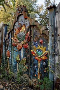 an artisticly painted wooden gate with flowers and birds on it's sides in the woods