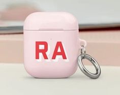 an airpods with the word ra printed on it and a keychain attached