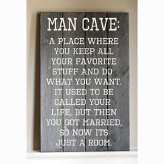 a wooden sign that says man cave on the side of a white shelf in front of a wall