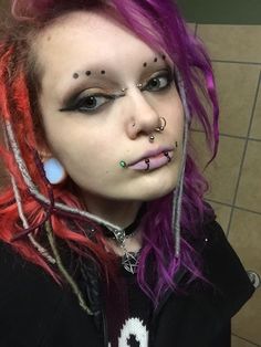 a woman with pink hair and piercings on her face