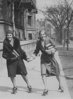 two women rollerblading down a street holding hands