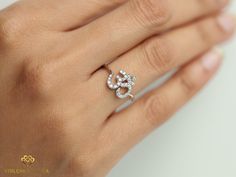 a woman's hand with a diamond ring on top of her finger and the word love written in white gold