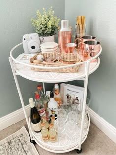 a white bar cart filled with bottles and glasses on top of a carpeted floor