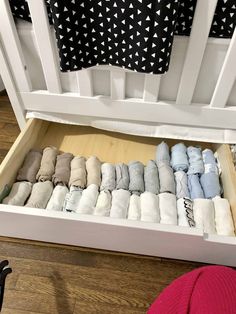 an open drawer filled with folded towels on top of a wooden floor