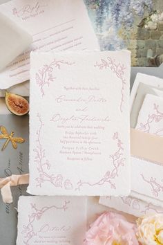 the wedding stationery is laid out on top of each other, including paper and flowers