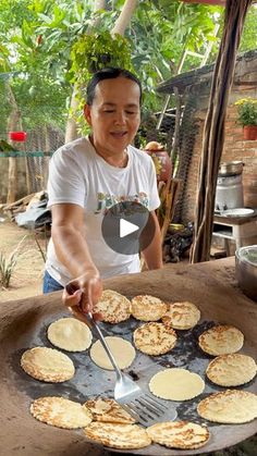 a man is making pancakes on an outdoor grill